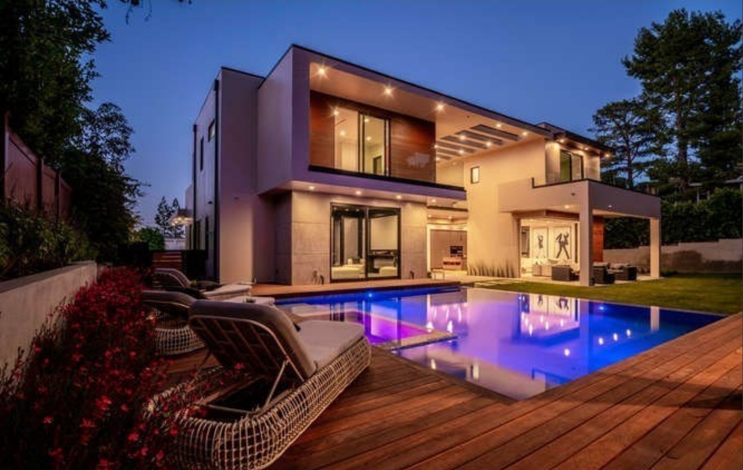 Pool lit at night with the house behind it