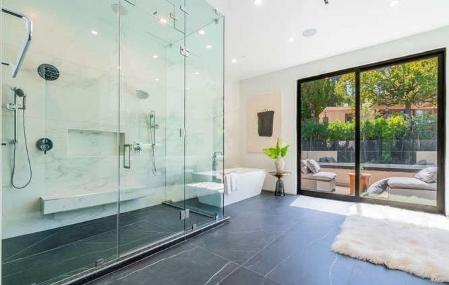Glass-enclosed shower with marble walls