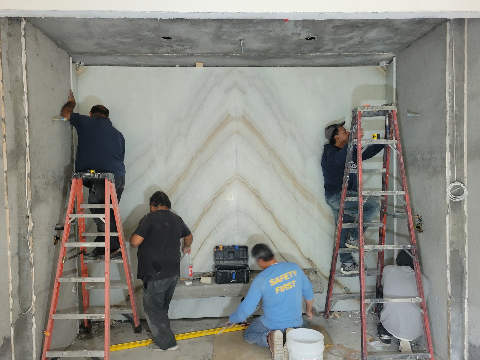 Crew installing a book-matched marble feature wall — Boca de Canon custom home build in Brentwood, Los Angeles